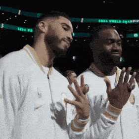 a couple of men standing next to each other on a basketball court .