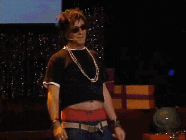 a man is walking on a stage with gifts behind him