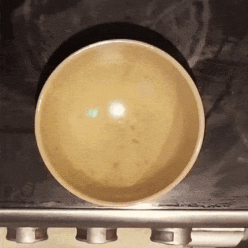 a bowl is sitting on a stove with a black background