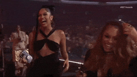 two women are laughing together on a stage at a concert