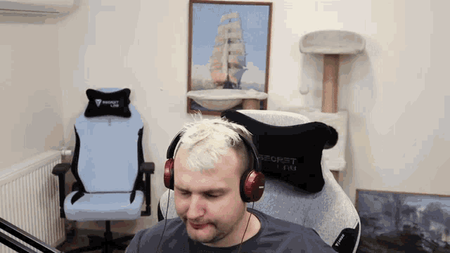 a man wearing headphones sits in a room with a blue chair and a black pillow that says secret lab