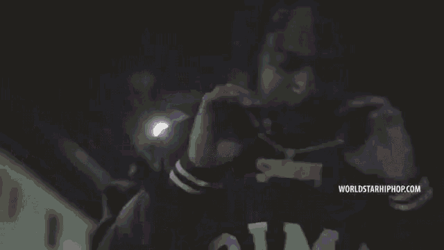 a person wearing a purple shirt with the word rim3 on it is holding a gun .