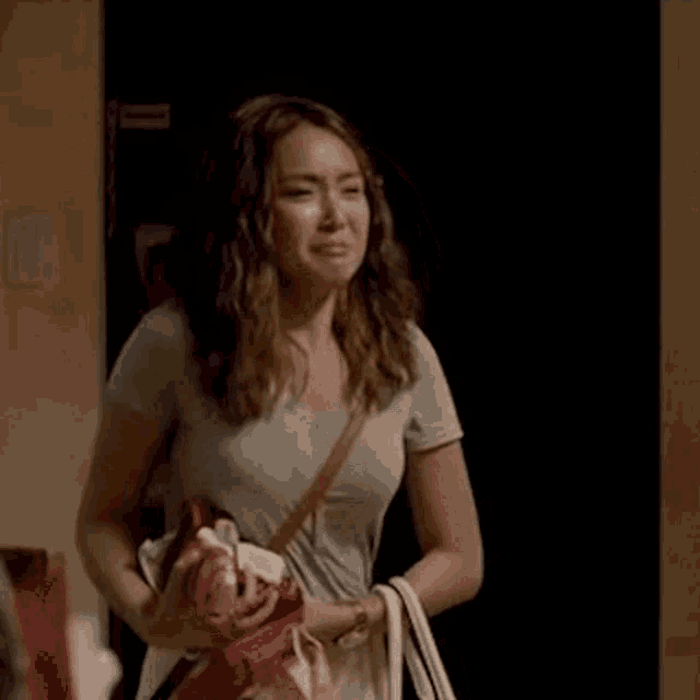 a woman is holding a purse and a pair of shoes in her hand .