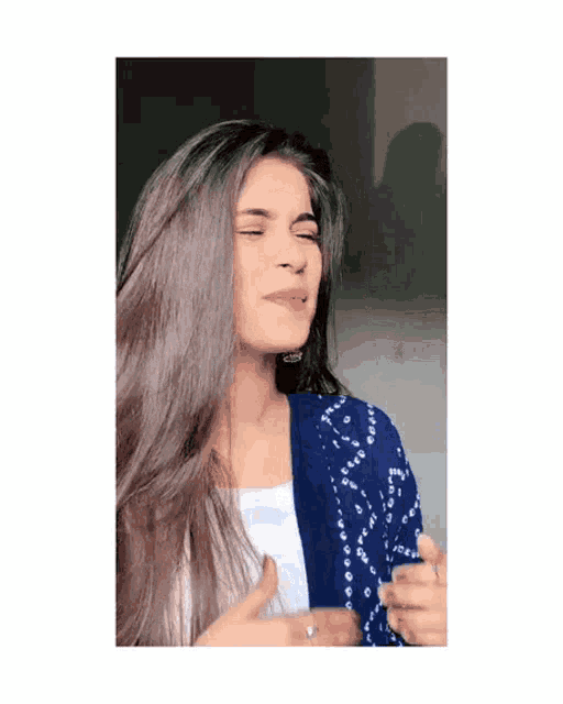 a woman with long hair is wearing a blue jacket and white shirt .