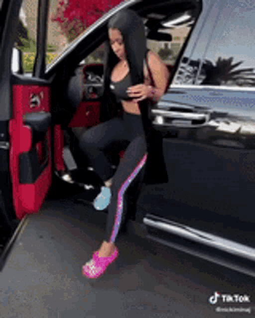 a woman with long black hair is getting out of a black car .