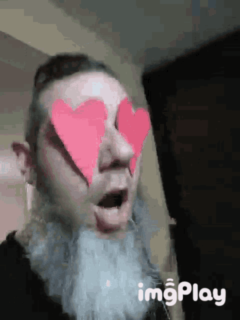 a man with a beard is wearing pink heart shaped glasses