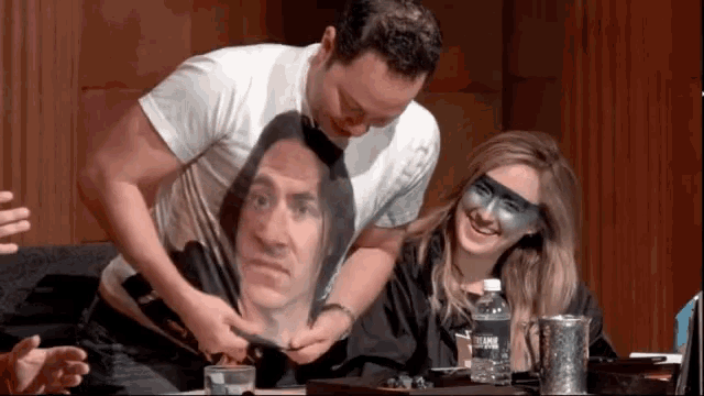 a man is putting a picture of a man on a woman 's shirt ..