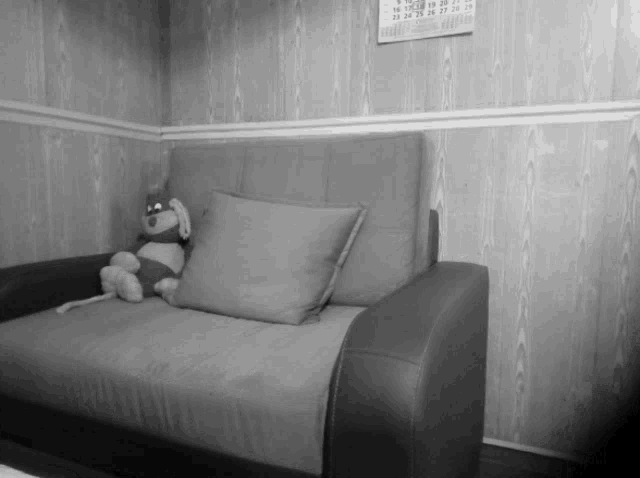 a black and white photo of a couch with a calendar on the wall above it