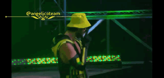 a man wearing a yellow hat stands in front of a crowd of people
