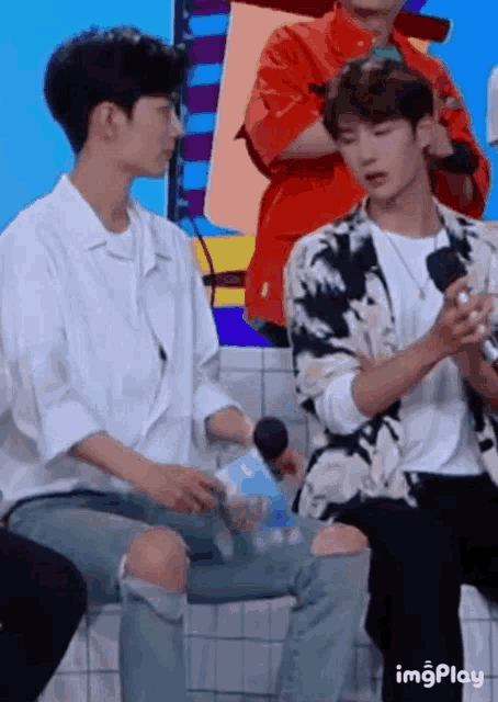 two young men are sitting next to each other on a stage .