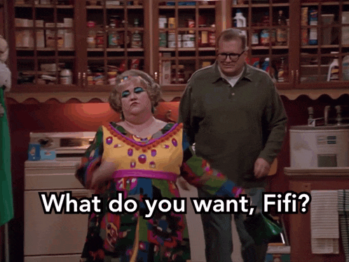 a woman in a colorful dress is standing next to a man in a kitchen and says what do you want fifi