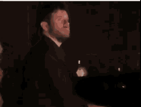 a man is covering his face with his hand while standing on a stage in a dark room .