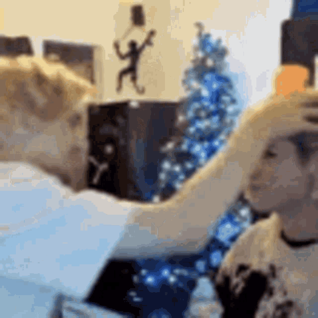 a man is putting his hand on a woman 's head in a room with a christmas tree in the background .