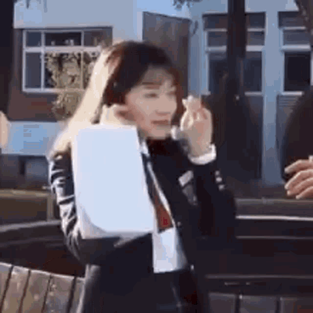 a woman in a suit and tie is holding a piece of paper in her hand and talking on a cell phone .