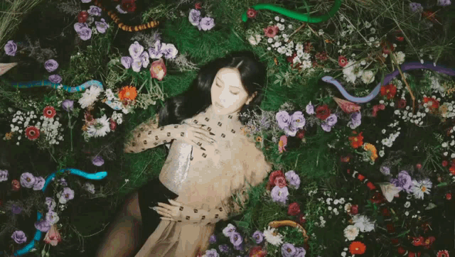 a woman is laying in a field of flowers with snakes