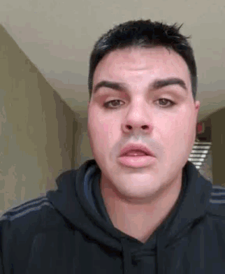 a man in a black hoodie is making a funny face and looking at the camera .