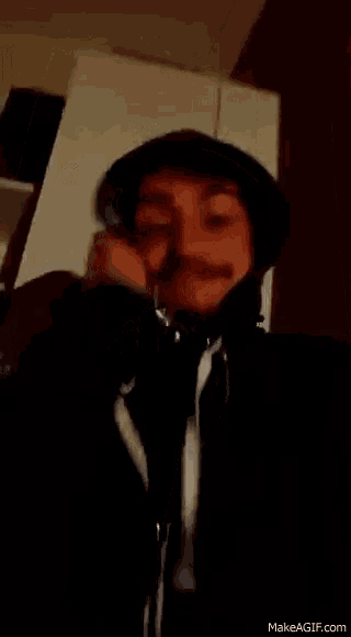 a man with a mustache is wearing headphones and a black hat