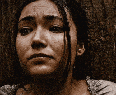 a close up of a woman 's face against a tree