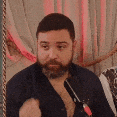 a man with a beard is talking into a black microphone