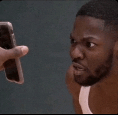 a man in a white tank top is looking at a phone