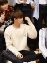 a man in a white sweater is sitting in front of a group of people .