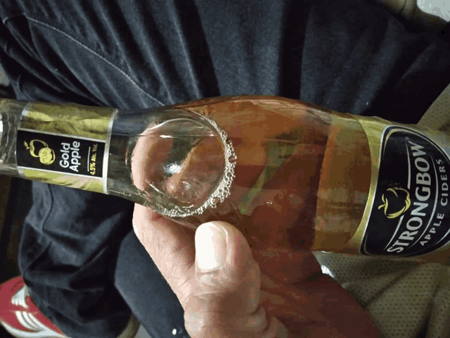 a person holding a bottle of strongbow apple ciders