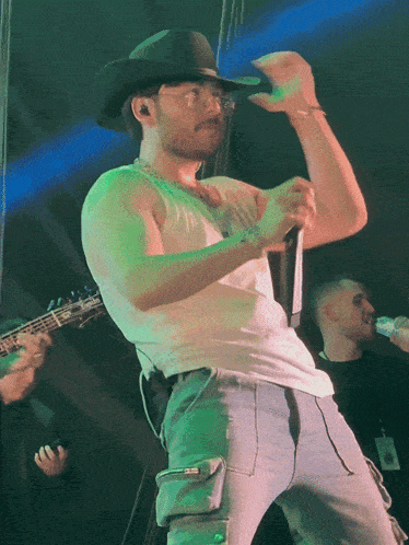 a man in a cowboy hat is singing into a microphone on stage