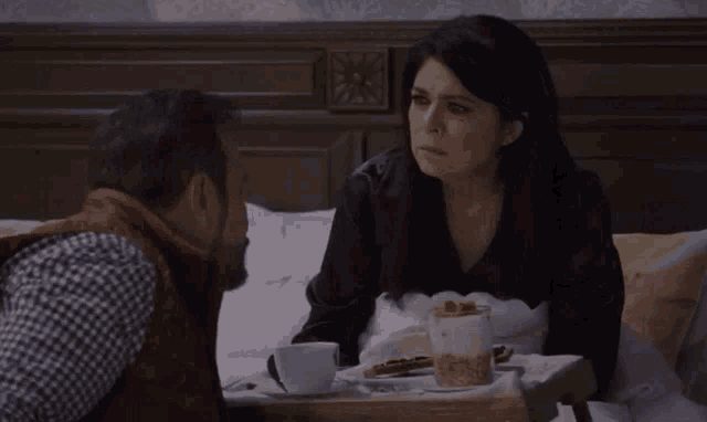a man and a woman are sitting at a table with food and drinks