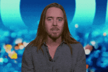 a man with long hair and a beard is wearing a gray shirt