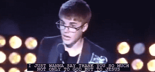 a man wearing glasses stands in front of a microphone and says i just wanna say thank you so much not only to god