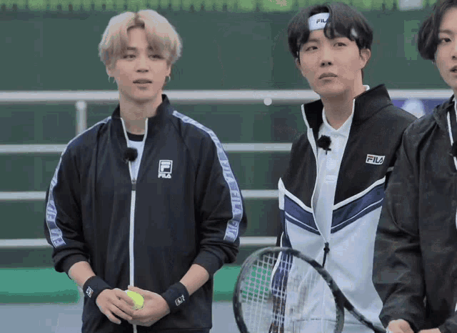 a man wearing a fila jacket holds a tennis racket
