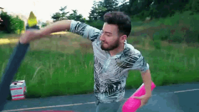 a man with a beard is throwing a frisbee down a road .