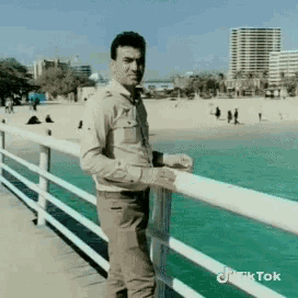 a man leaning on a railing overlooking a body of water with tiktok written on the bottom right