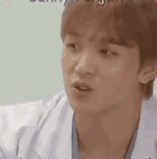 a man in a white coat is making a funny face while talking to someone .
