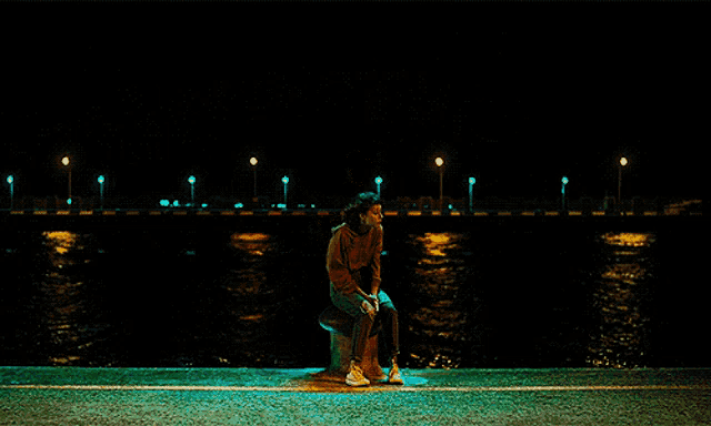 a man walking past a woman sitting on a bench near the water