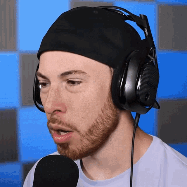 a man with a beard wearing headphones and a hat