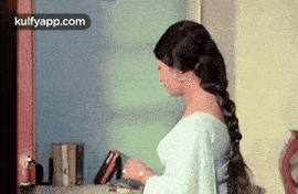 a woman in a blue dress is standing in front of a bookshelf .