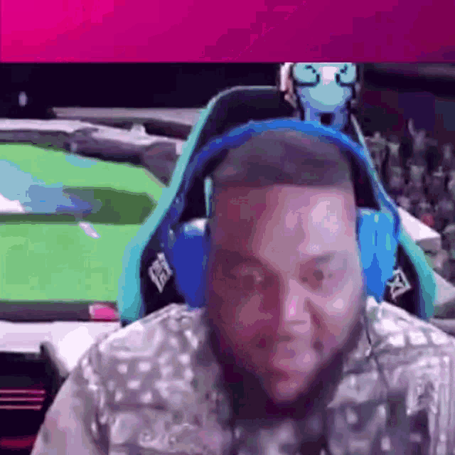 a man wearing headphones is sitting in a chair with a green screen behind him