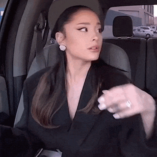ariana grande is sitting in the back seat of a car wearing a hat and a blazer .
