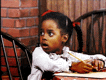 a little girl is sitting at a table with a pencil