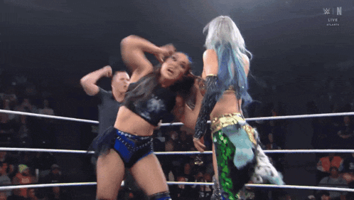 two women are wrestling in a ring with the letters n on the bottom left