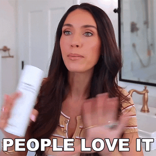 a woman is holding a bottle of shampoo and says people love it