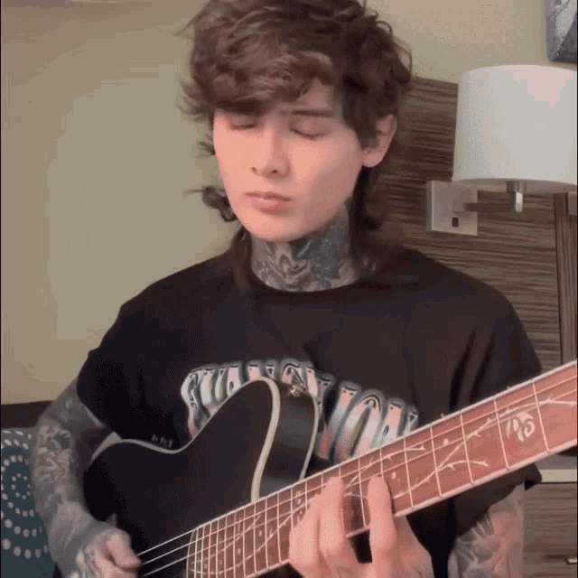 a man playing a guitar wearing a shirt that says ' guns n roses '