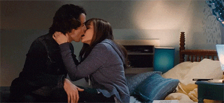 a man and a woman are kissing on a bed in a bedroom