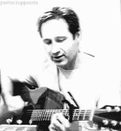 a black and white photo of a man playing an acoustic guitar .