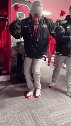 a man in an ohio state jacket holds a red rose