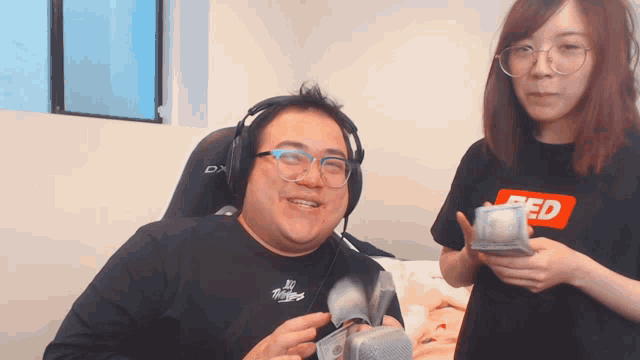 a man wearing headphones and a woman wearing a shirt that says red