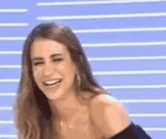 a woman is smiling and laughing in front of a blue background .