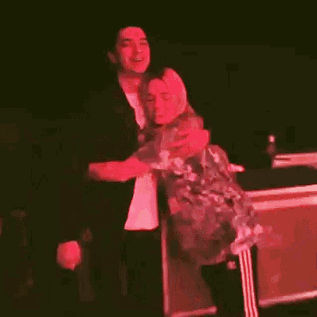 a man and a woman are hugging on a stage in the dark
