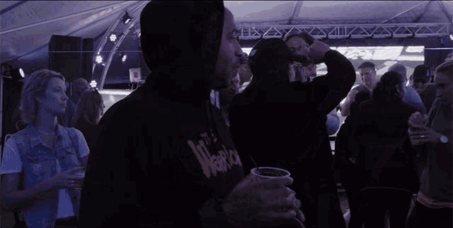 a man wearing a hoodie that says the warriors holds a cup of beer